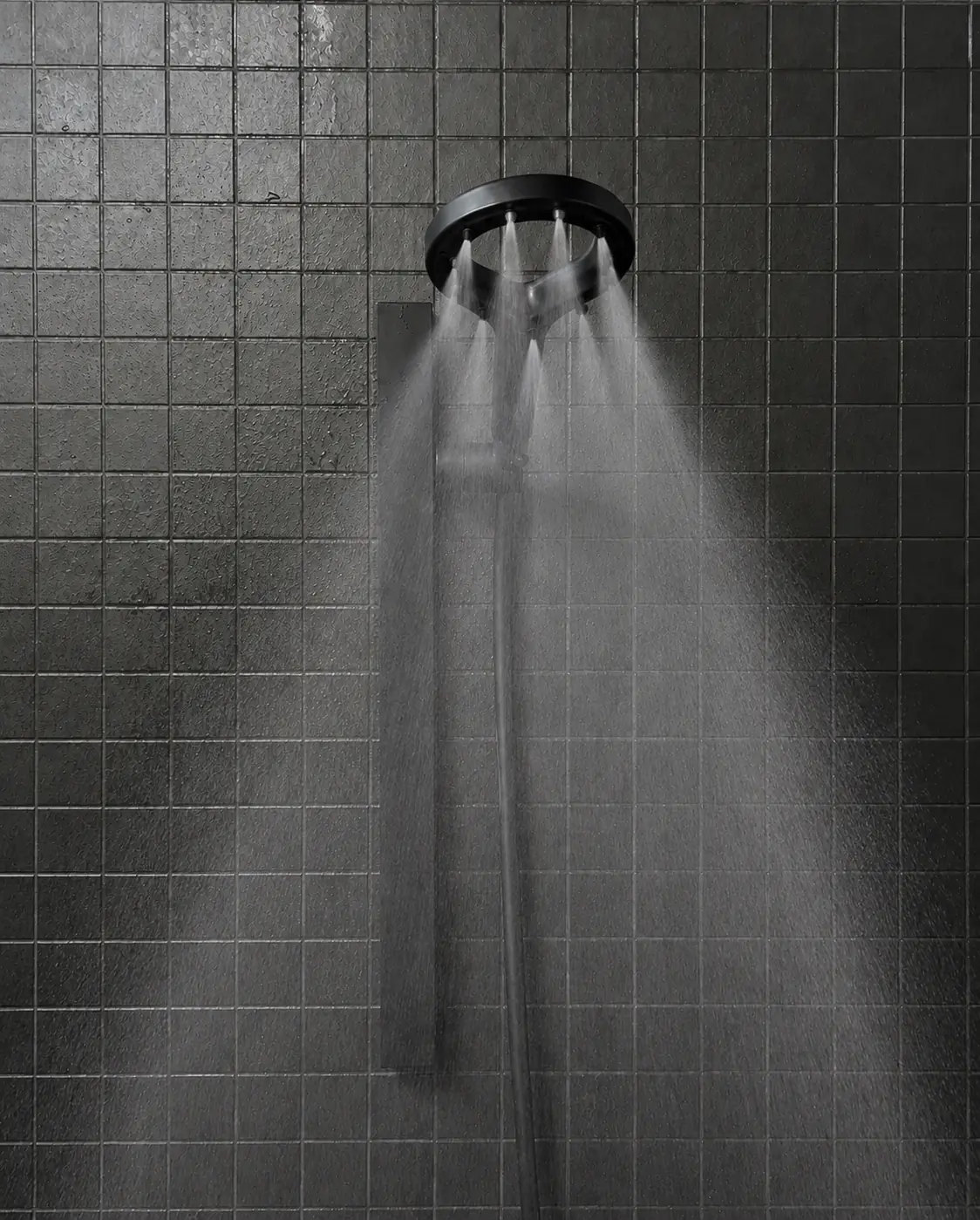 Olsek Halo delivering a wide spray against a dark tiled shower wall